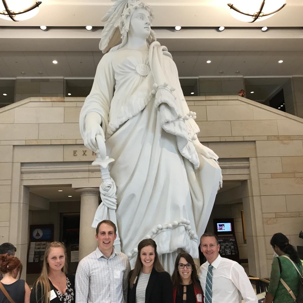 Five people are standing in front of the statue.